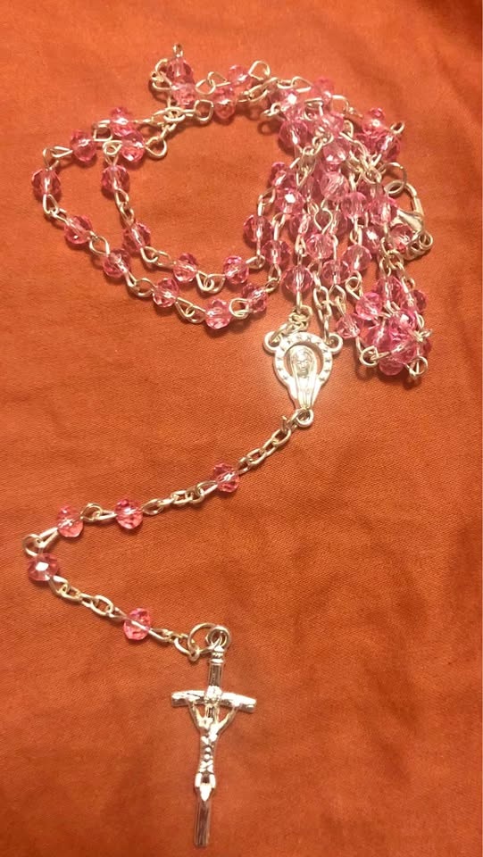 Pink rosary necklace in a small container