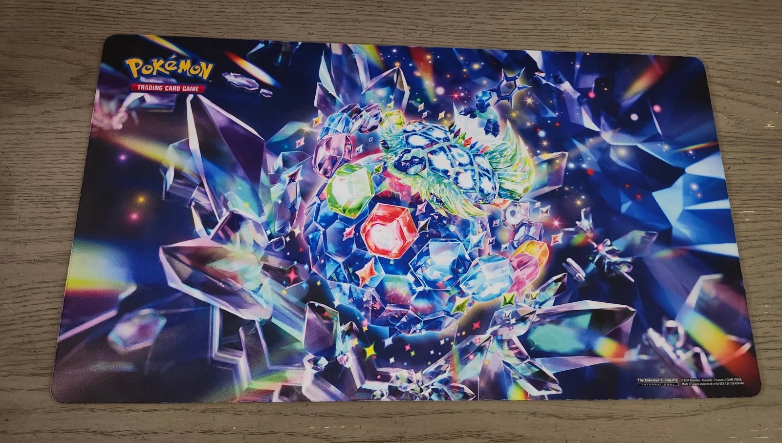 Official Pokémon-themed playmat featuring a multicolor crystal o