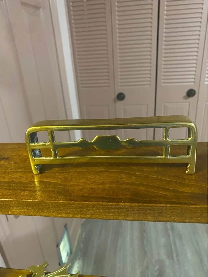 Antique brass ornament representing a fireplace fender.
