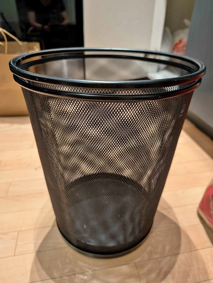 Two black metal mesh wastebaskets and slim blue recycling bin