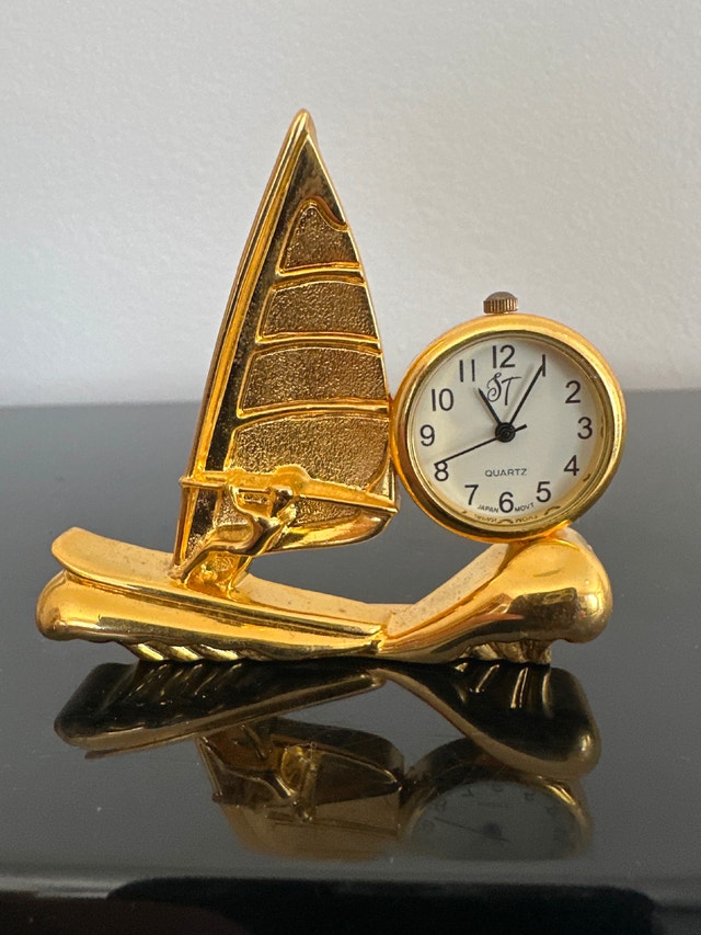 Vintage miniature gold quartz desk clock featuring a windsurfer