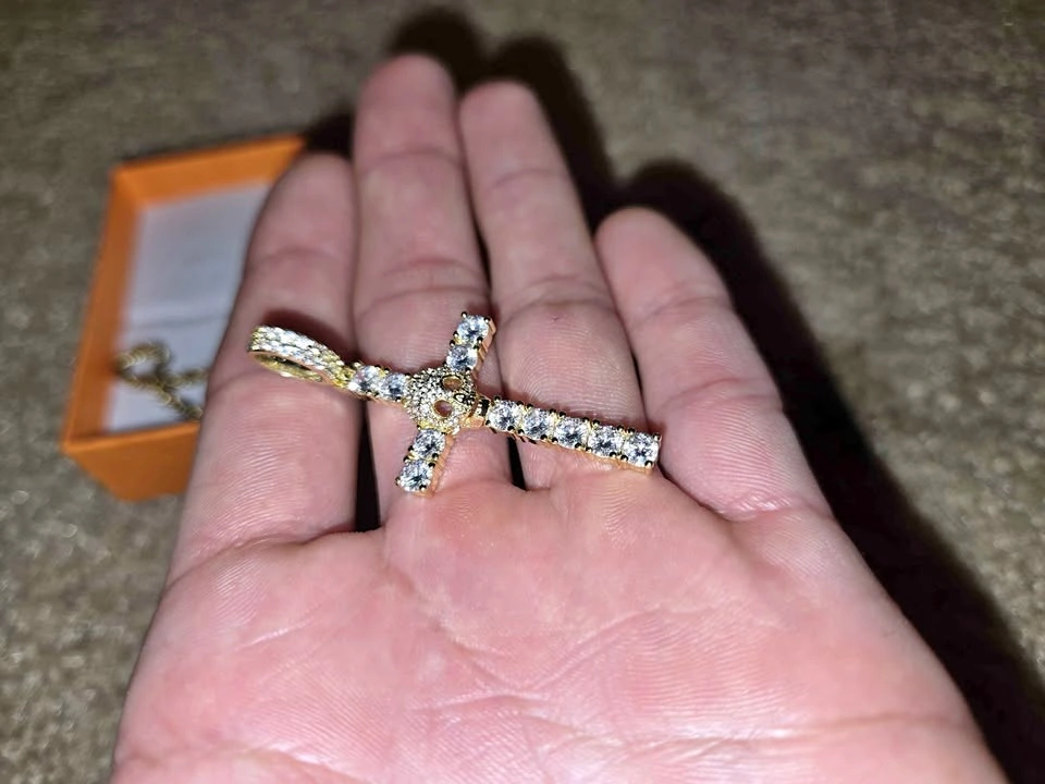 Gold chain with a cross-shaped pendant and a skull covered in zi