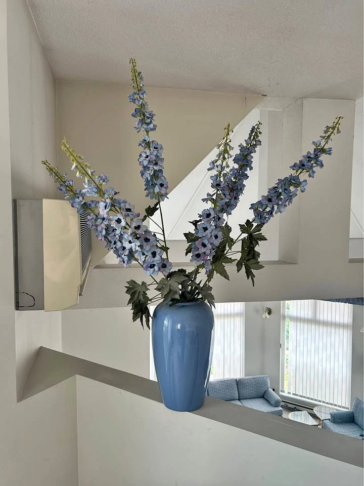 Tall faux flowers in blue vase