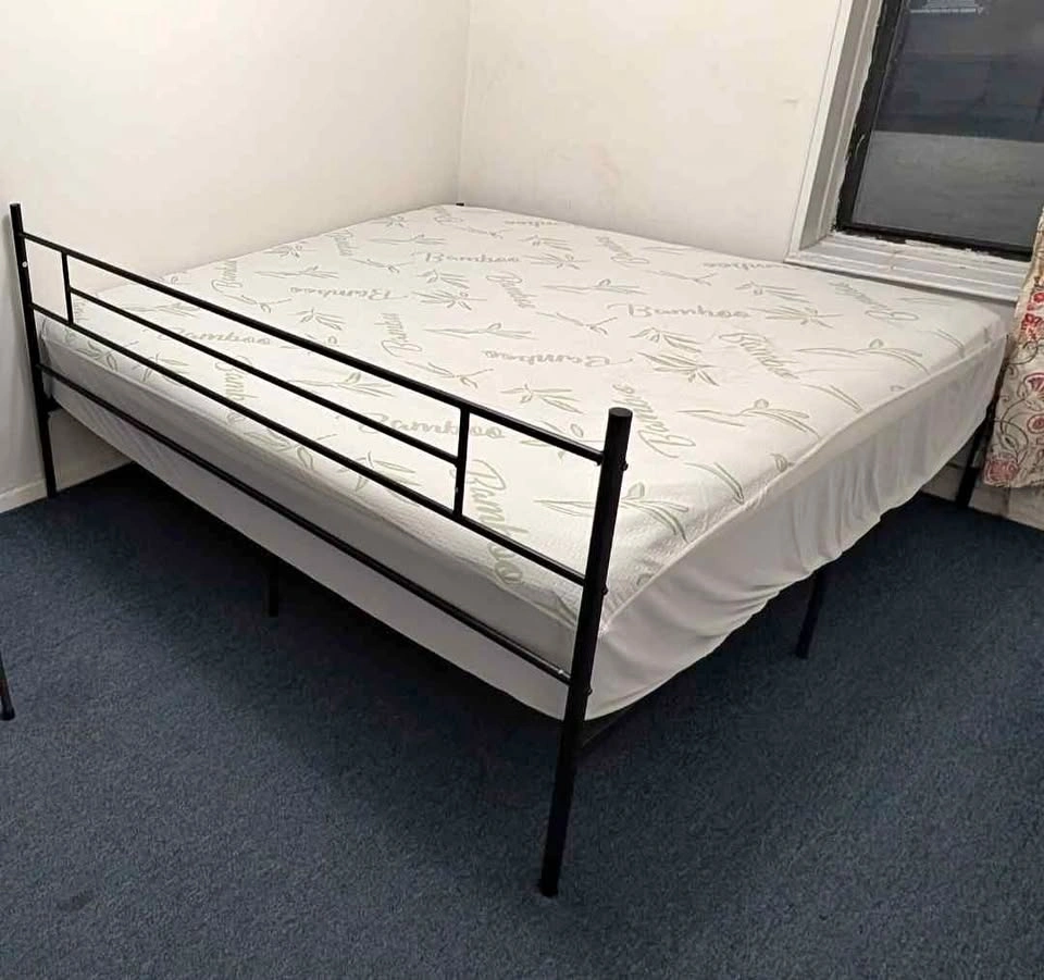 King-size metal bed frame with headboard, mattress, and cover