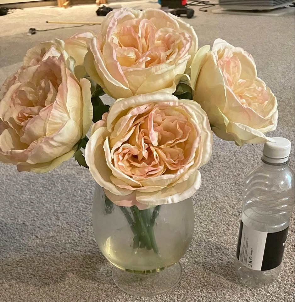 Beautiful fake roses in glass vase (water bottle for scale)