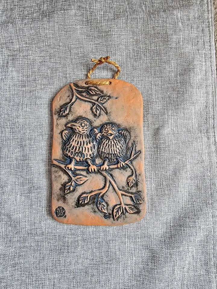 Terracotta relief wall plaque features two stylized birds