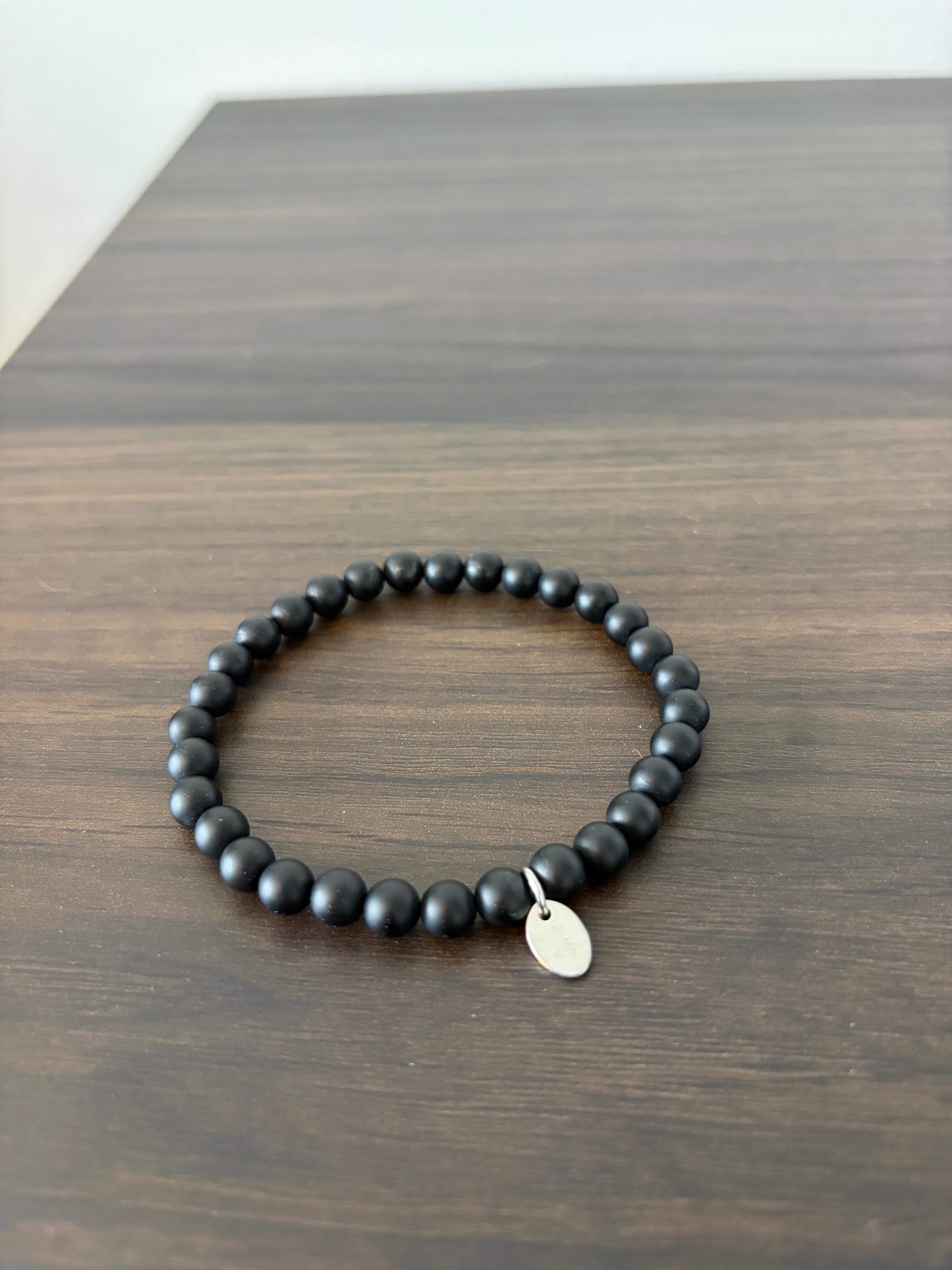 Tocara matte black bead bracelet with a oval charm tag