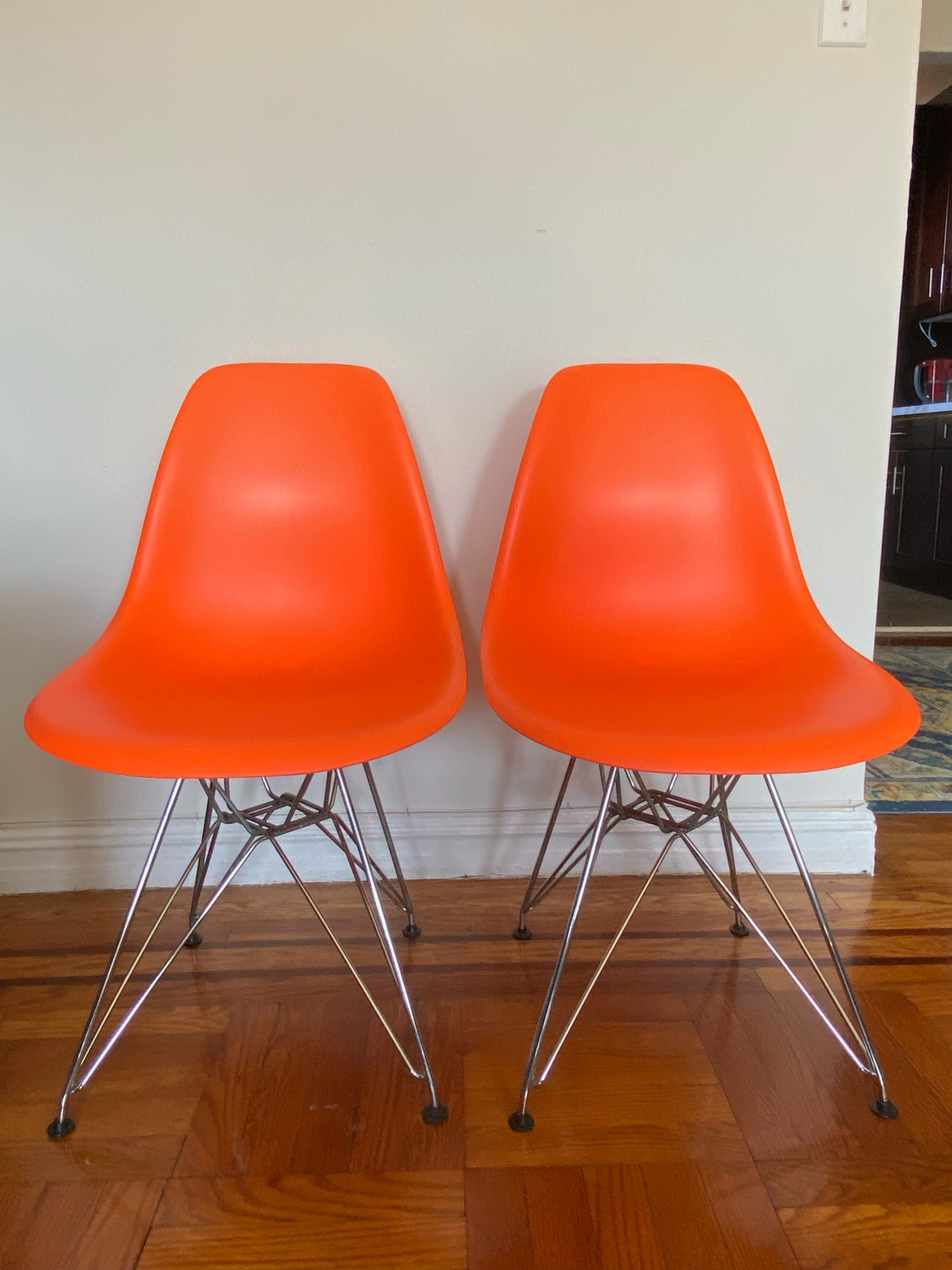 Two Orange Eames-Style Chairs with Chrome Eiffel Base