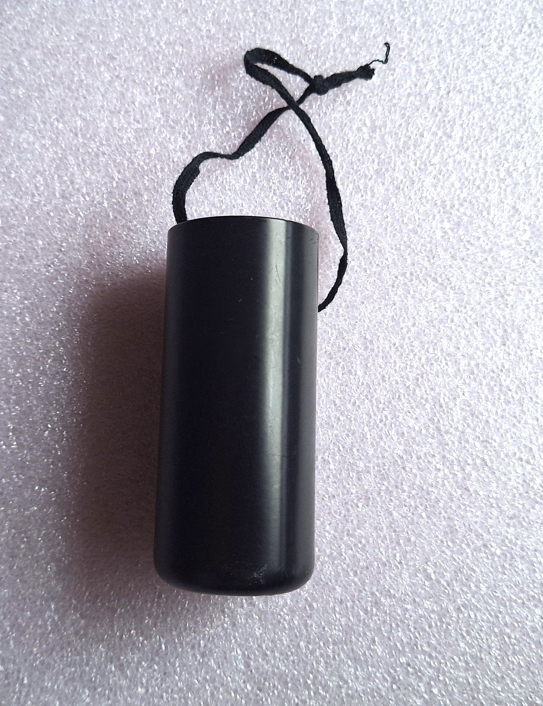 Black cylindrical container with hanging cord