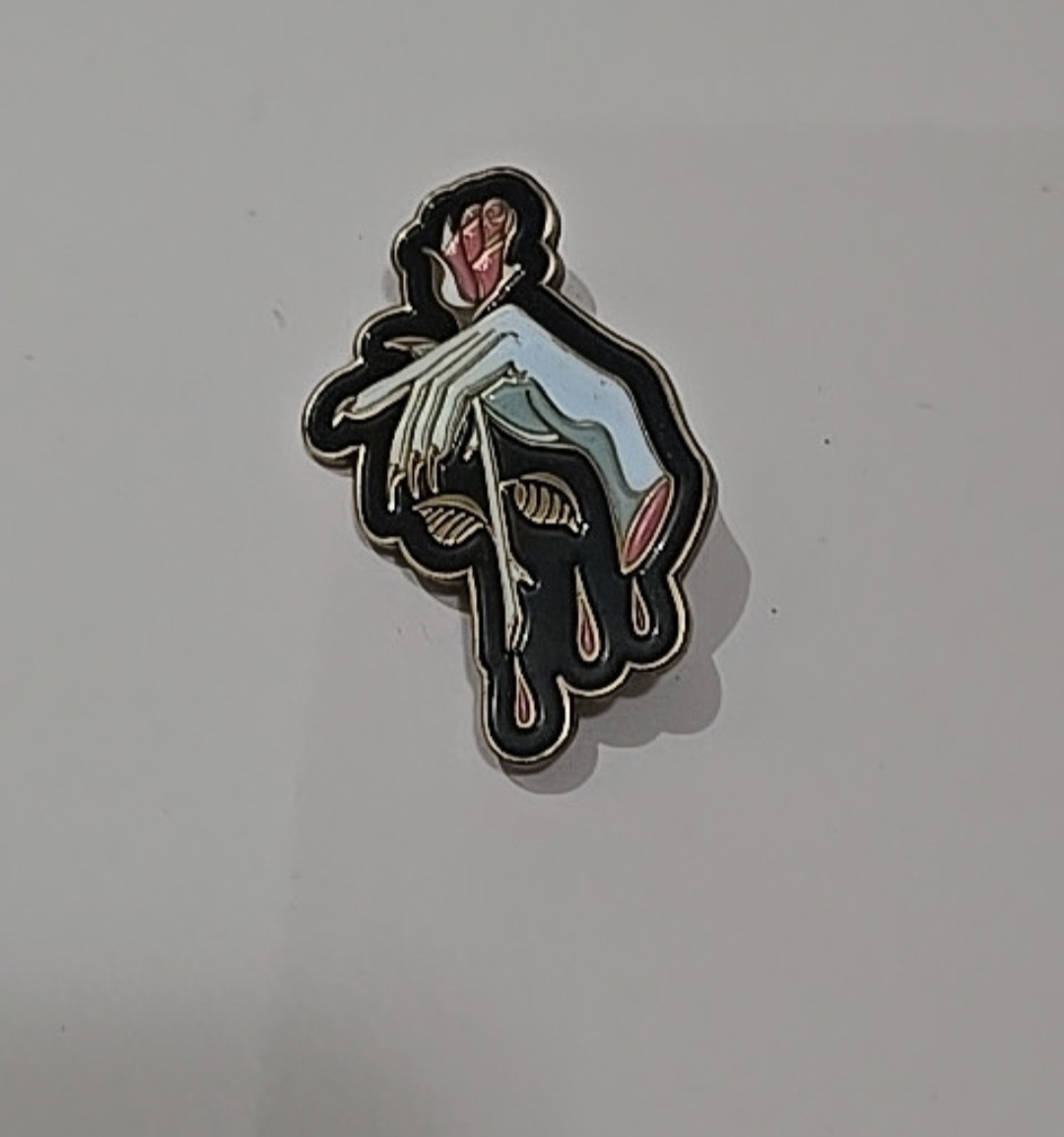 Hand holding rose enamel pin