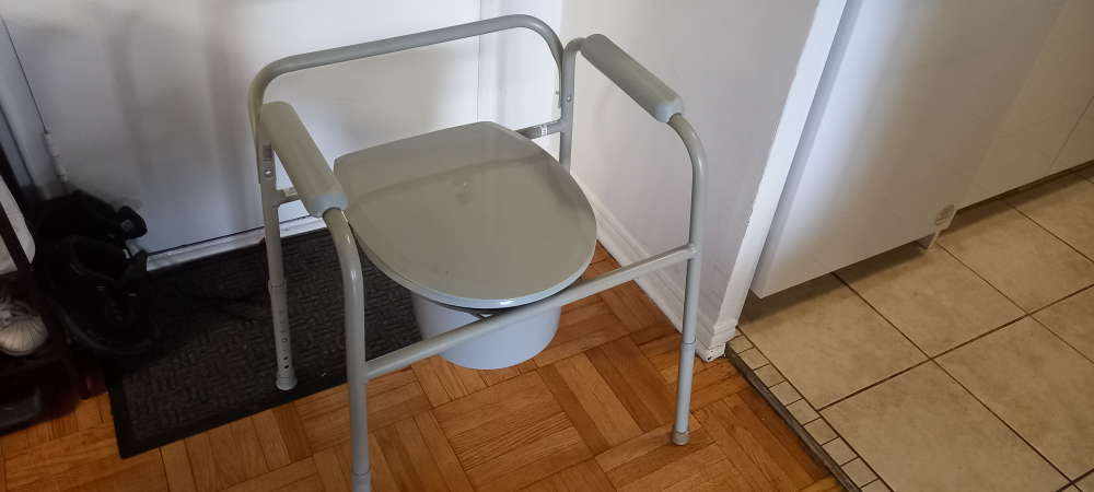 Grey bedside commode with armrests