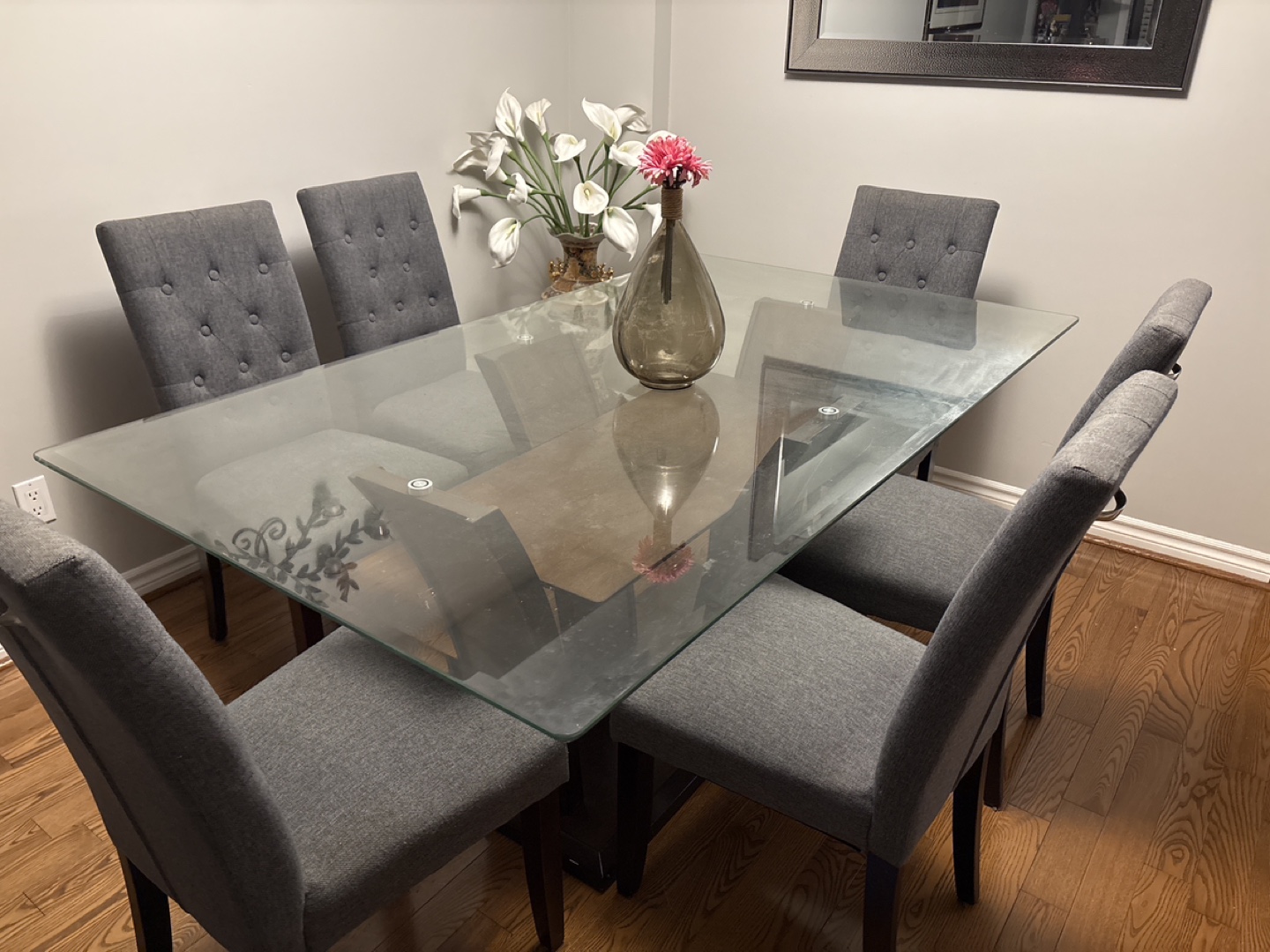 Glass-top dining table with six grey chairs