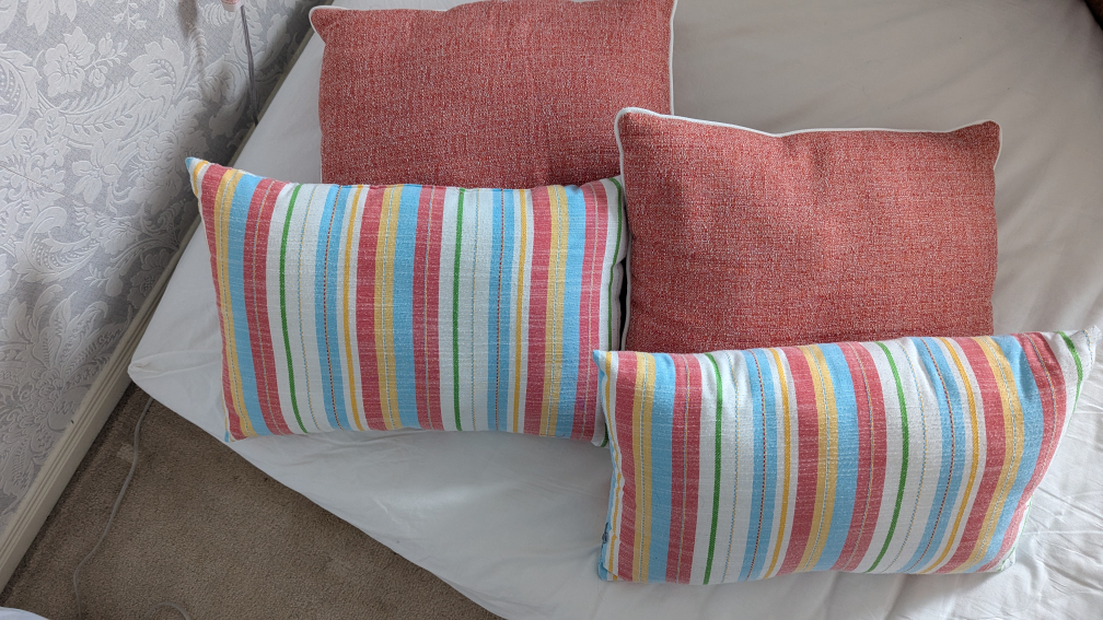 Four decorative pillows – two peach, two striped
