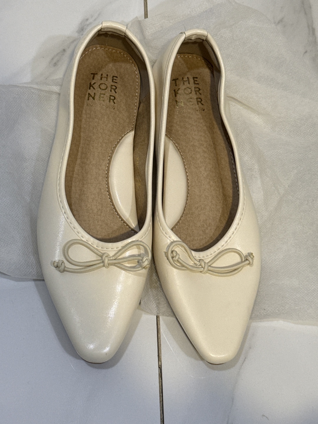 Cream-coloured pointed-toe flats with bows
