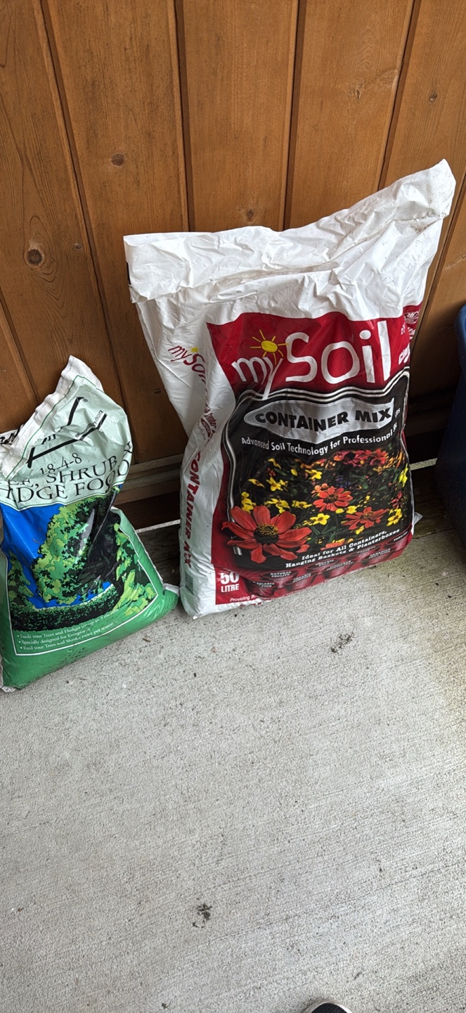 Two bags of potting soil and a storage container