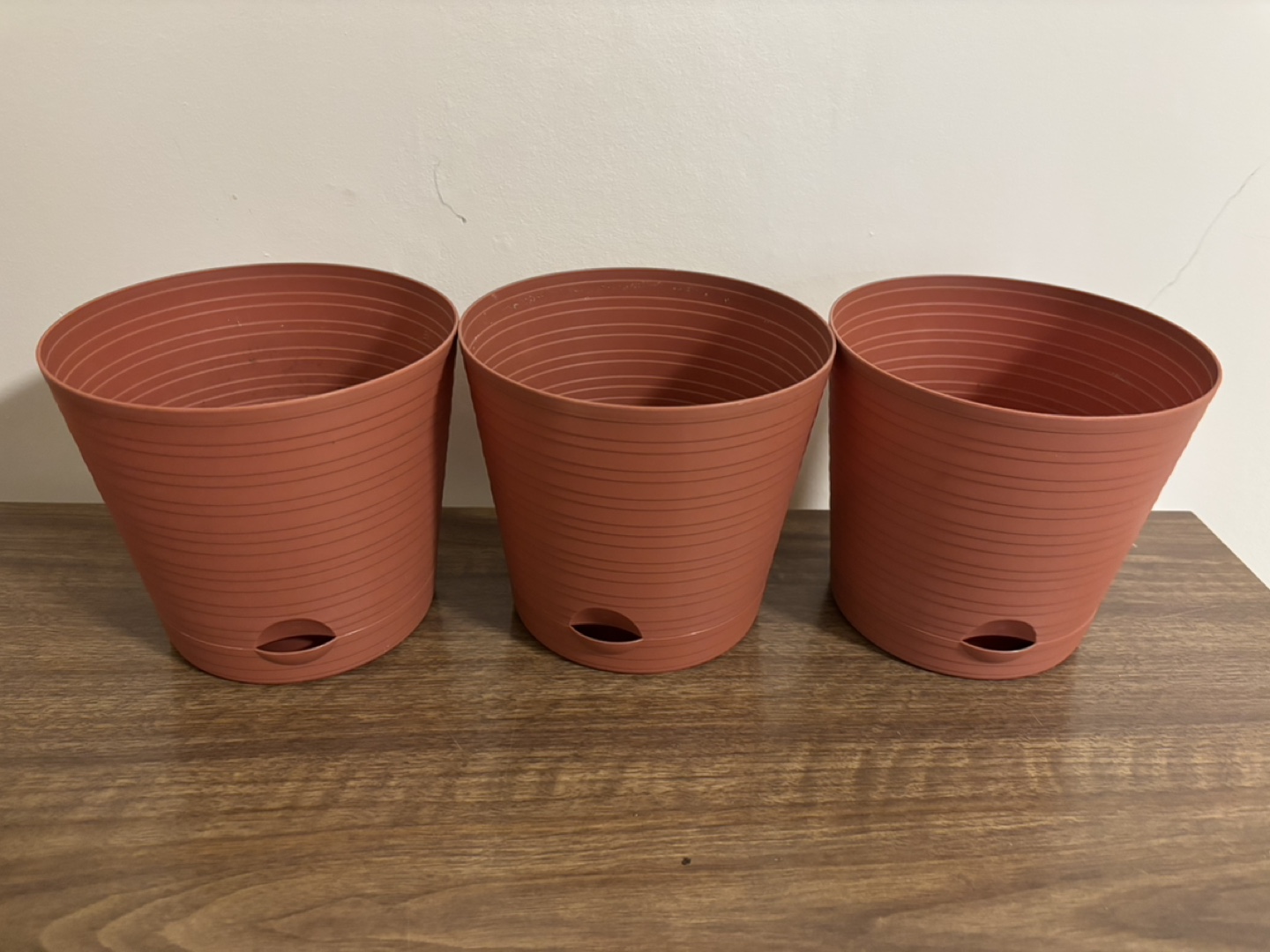 Three terracotta coloured plastic plant pots