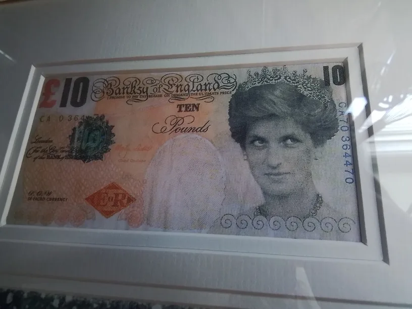 Framed Banksy artwork featuring a mod-d £10 note and a snowman image indicator(3)