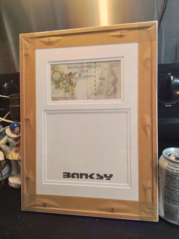 Framed Banksy artwork featuring a mod-d £10 note and a snowman image indicator(5)