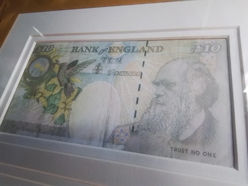 Framed Banksy artwork featuring a mod-d £10 note and a snowman image indicator(6)