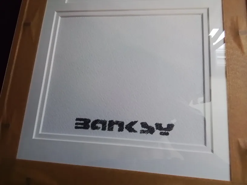 Framed Banksy artwork featuring a mod-d £10 note and a snowman image indicator(7)
