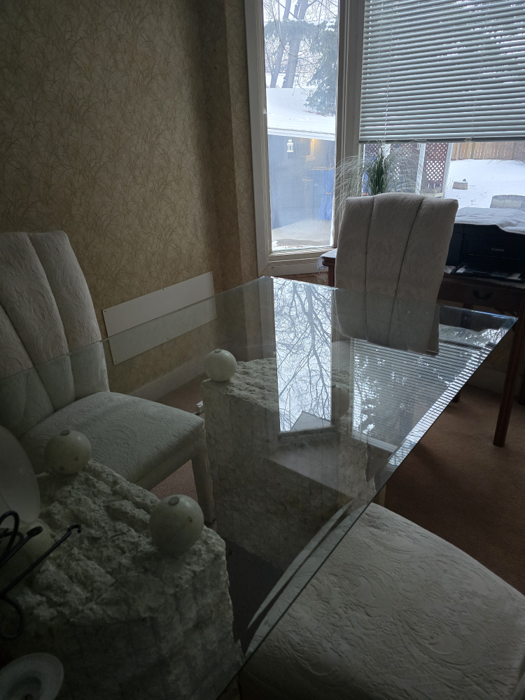Glass-top dining table with unique stone base and four chairs