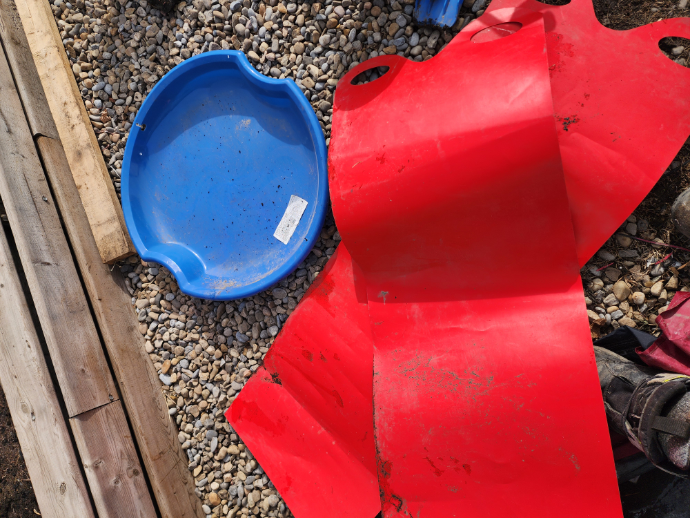 Blue plastic sled and red plastic mat