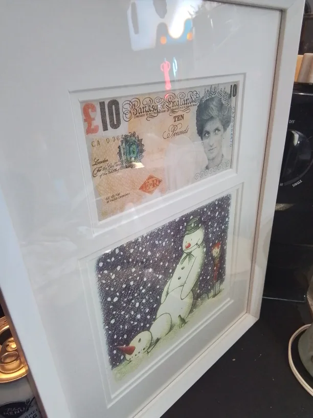 Framed Banksy artwork featuring a mod-d £10 note and a snowman image indicator(9)