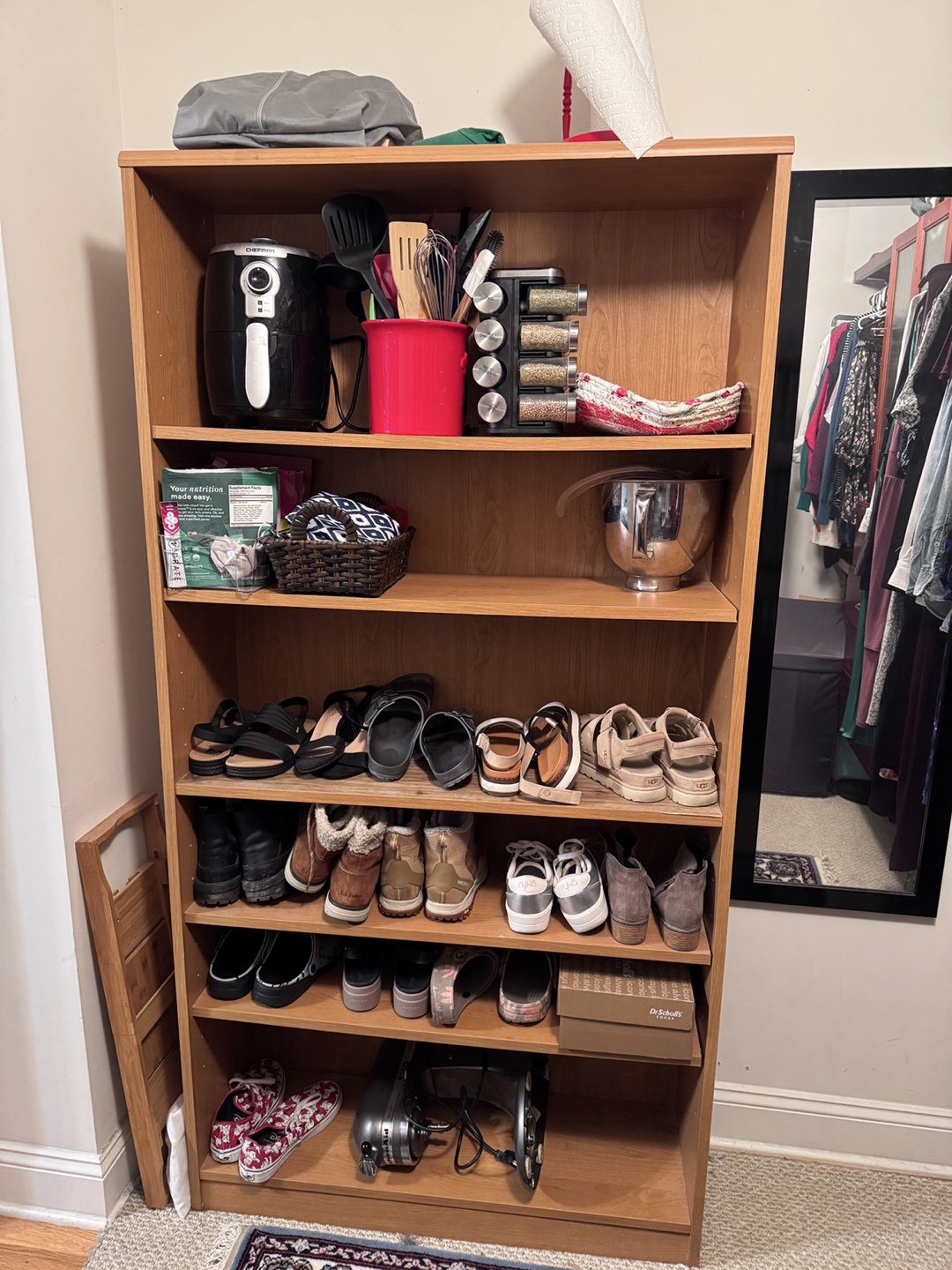 Multi-shelf wooden bookcase with shoes and kitchen items