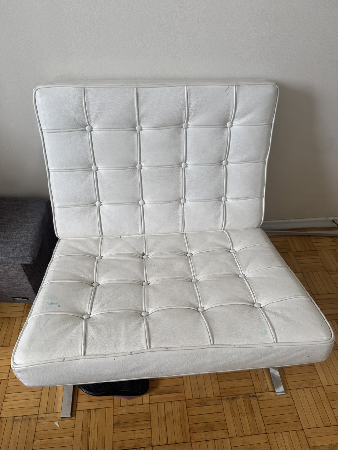 white Barcelona chair, The chair features a stainless steel.