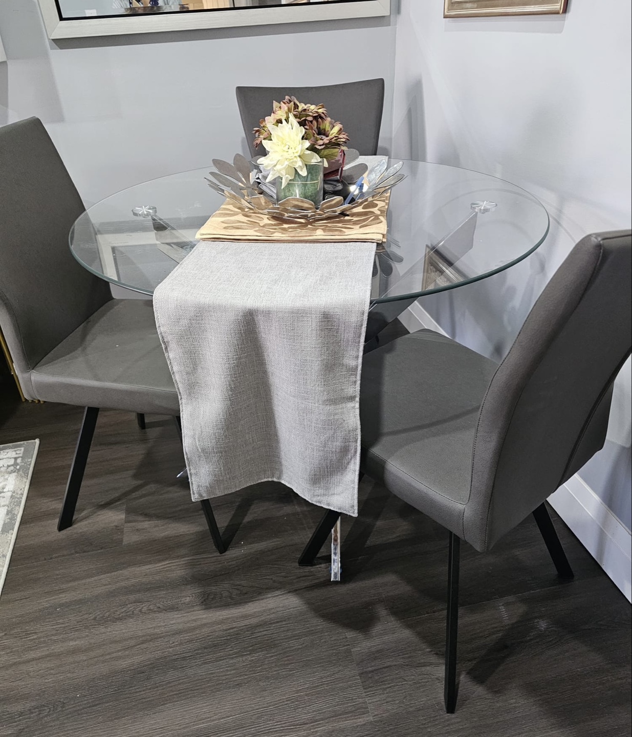 Glass top dining table with four grey chairs