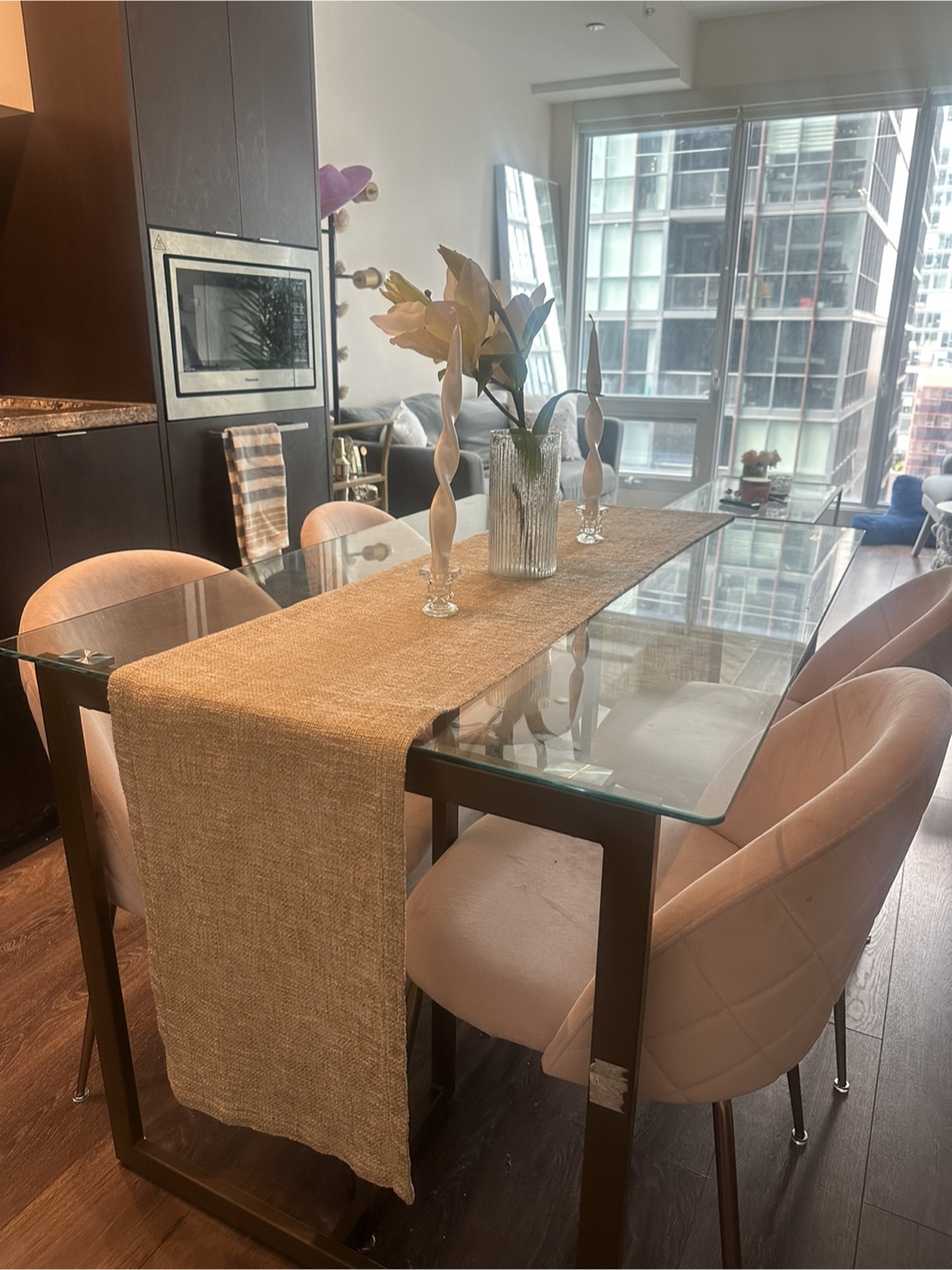 Glass-top dining table with four blush pink velvet chairs