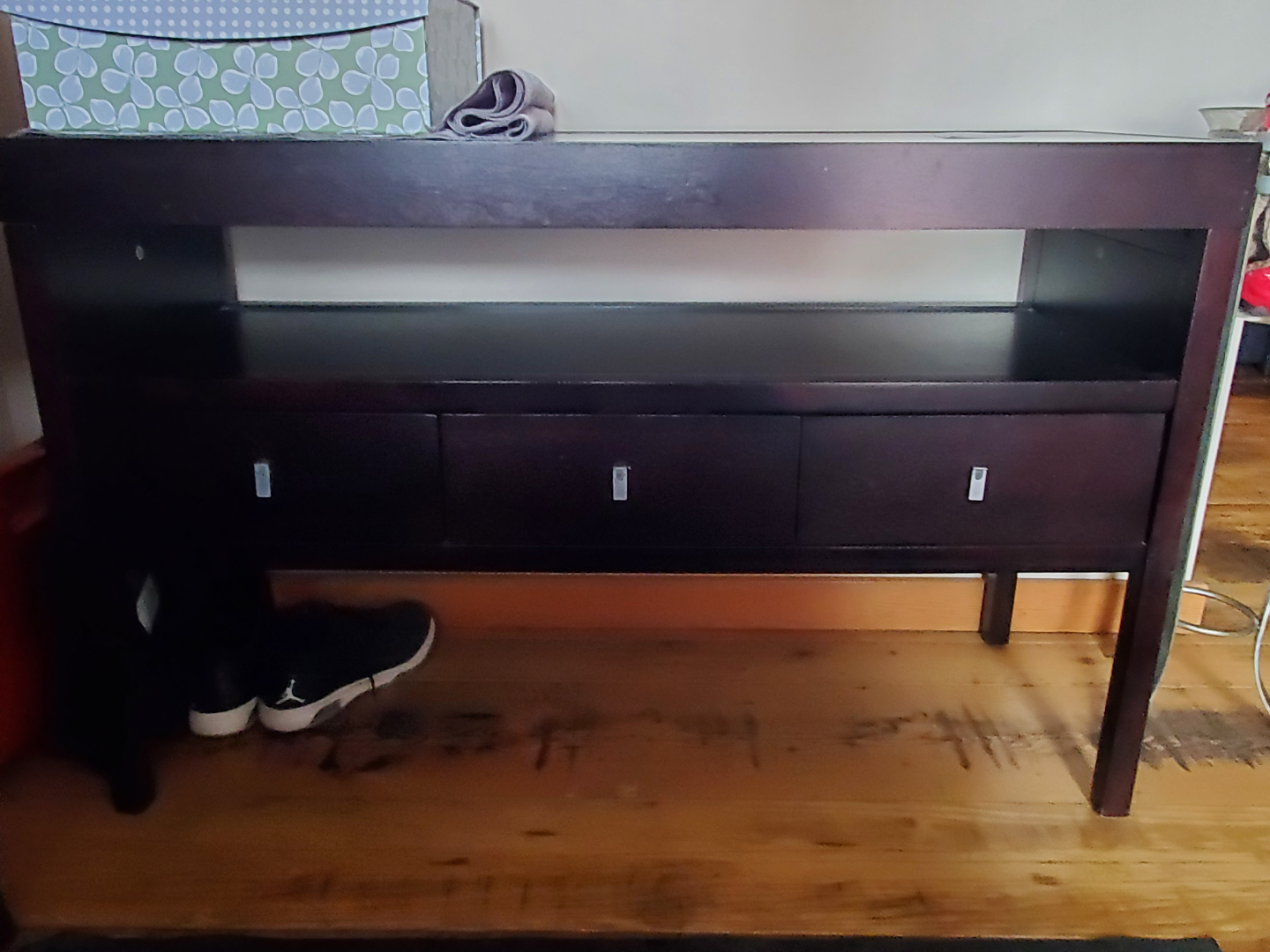 Dark brown wood console table with three drawers and glass top