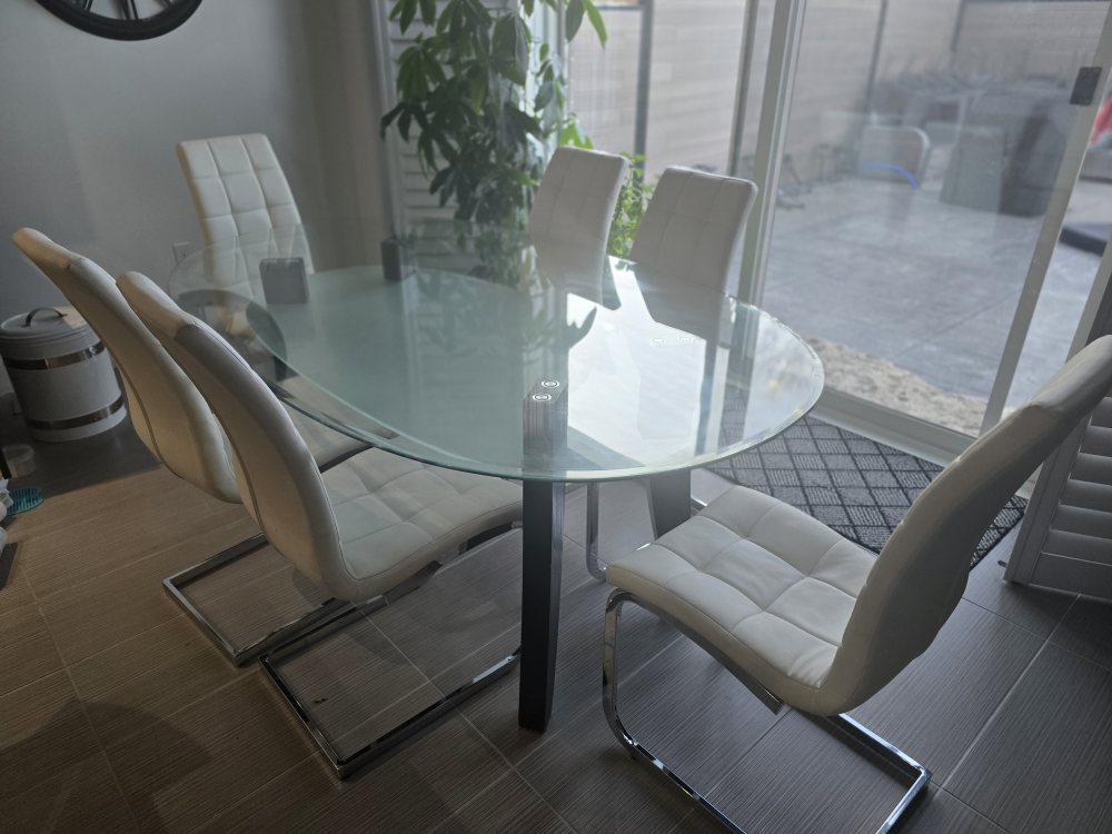 Glass-top dining table and six white chairs