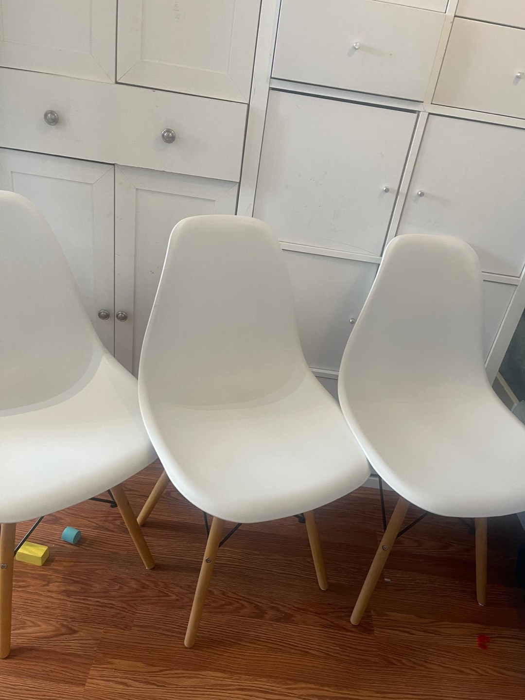 Set of three white plastic chairs with wooden legs