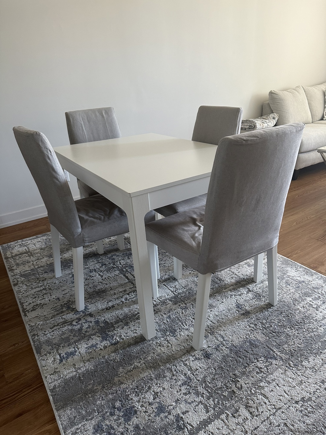 White extendable dining table with four grey chairs from IKEA