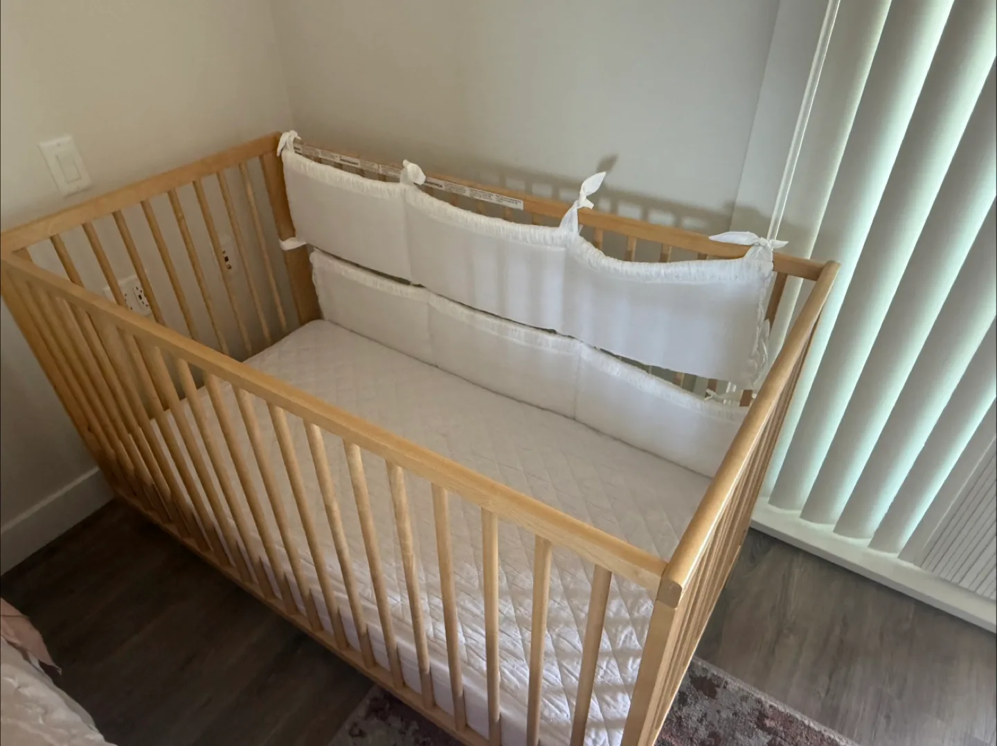 Wooden Baby Crib with White Bumper Pads thumbnail