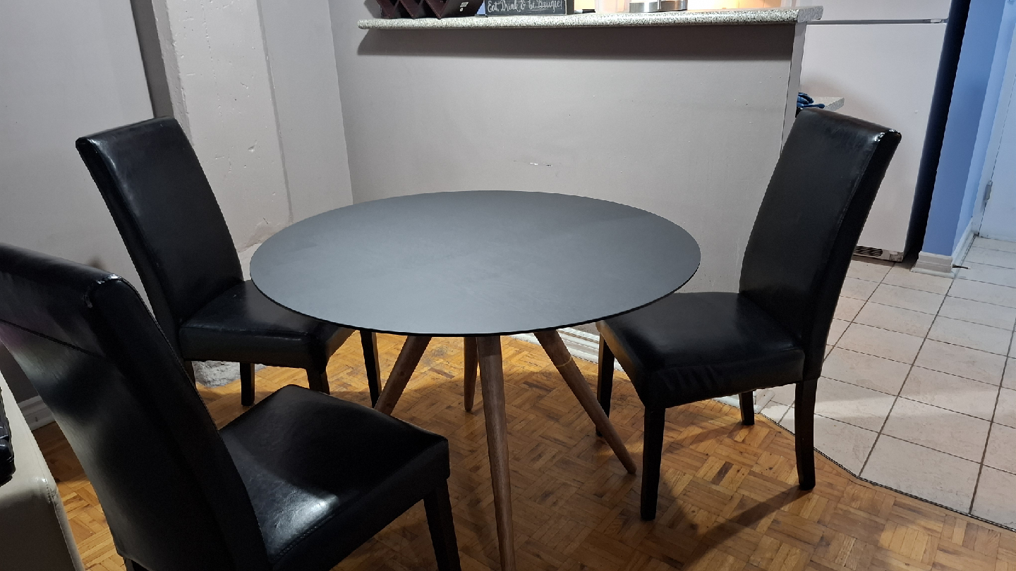 Round matt black wooden dining table with 3 black chairs