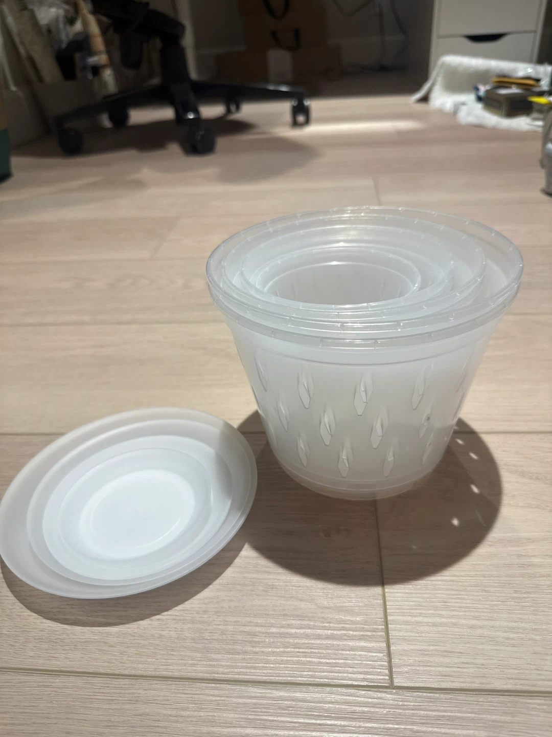 Set of clear plastic plant pots with saucers