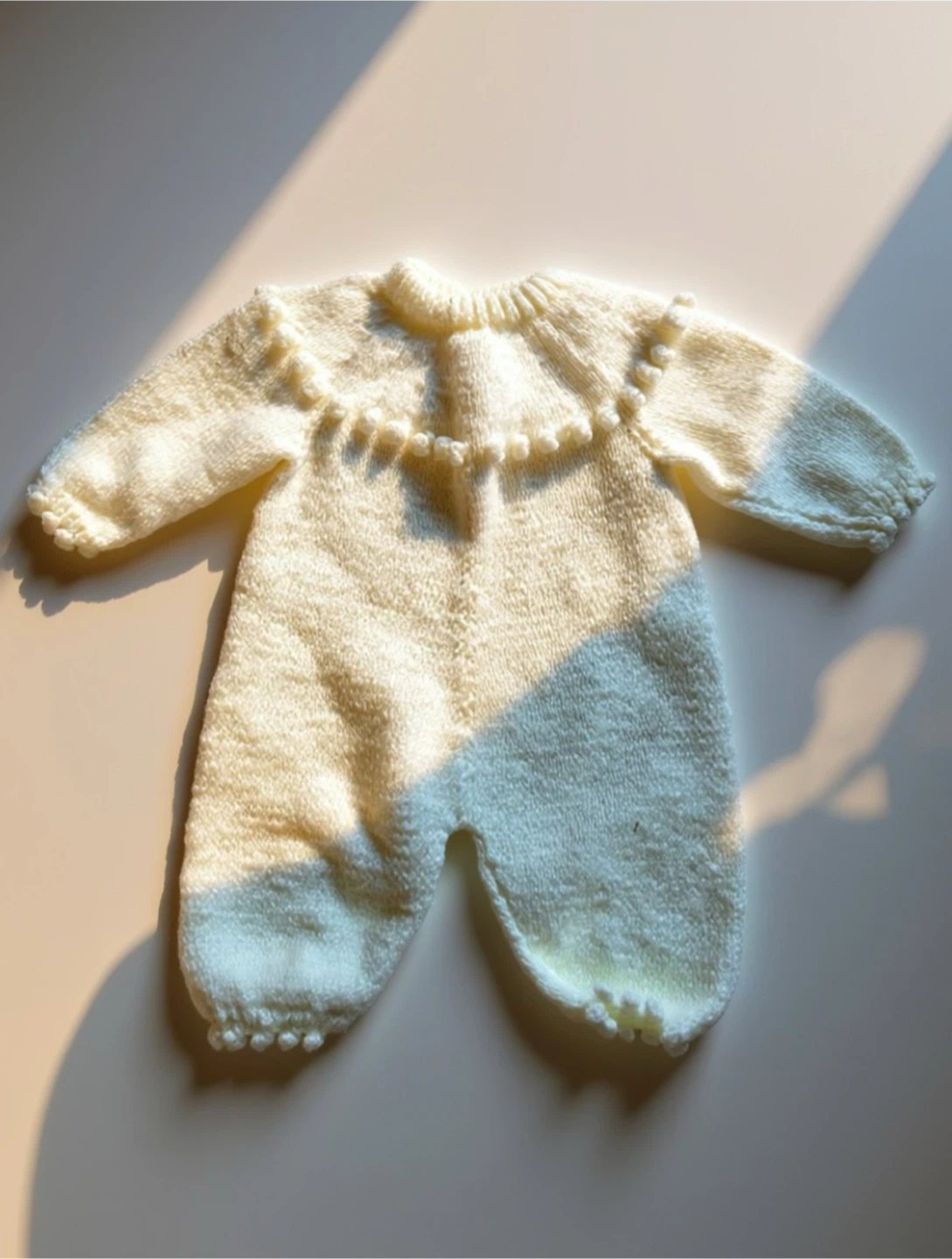 Handmade knitted baby romper with pom poms