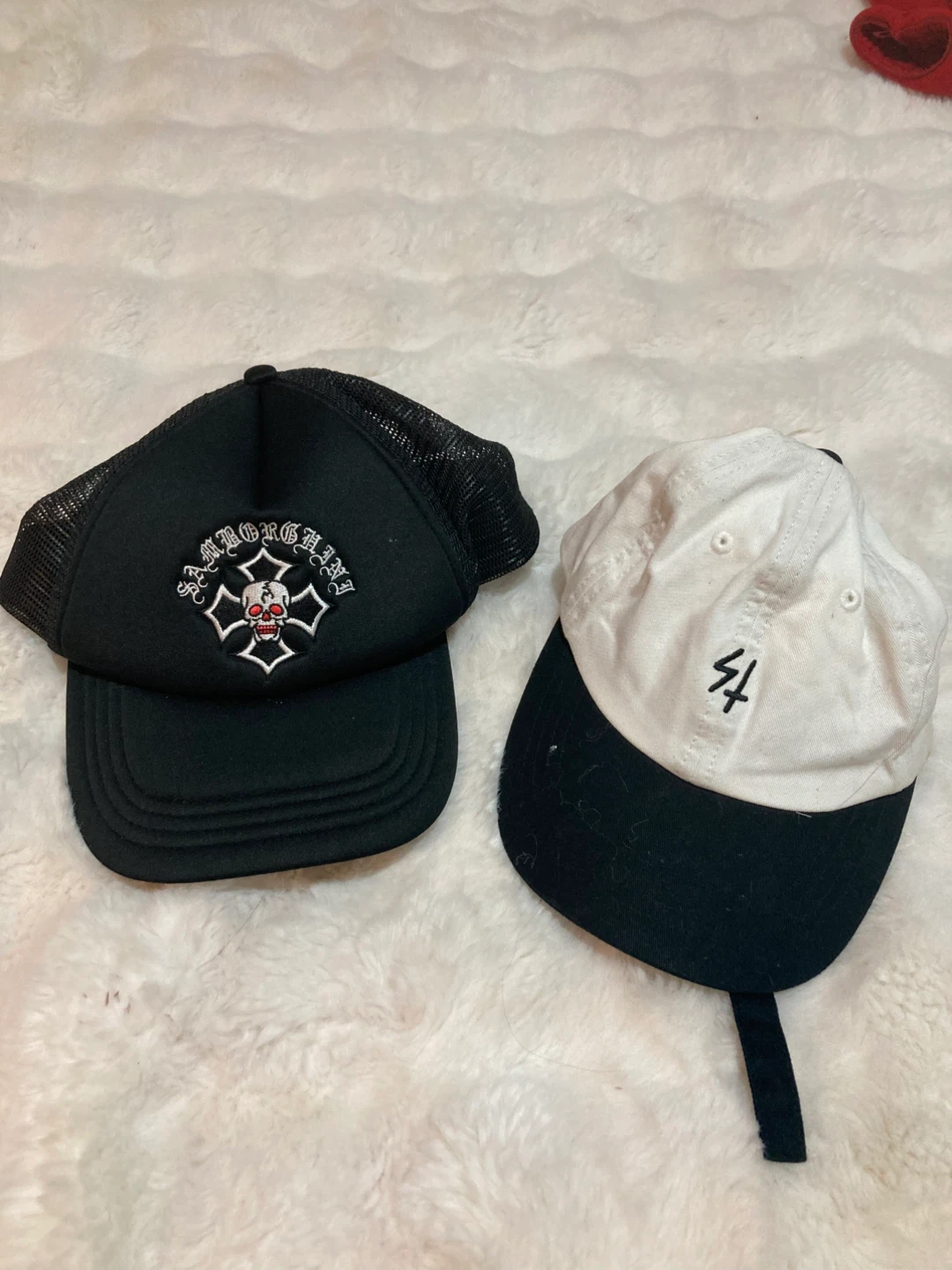 Two hats: black trucker hat and white/black baseball cap