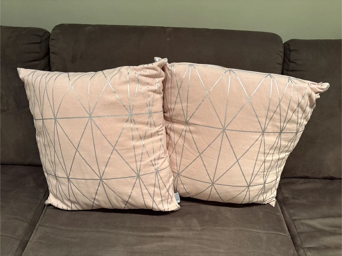 Two light pink throw pillows with silver geometric pattern