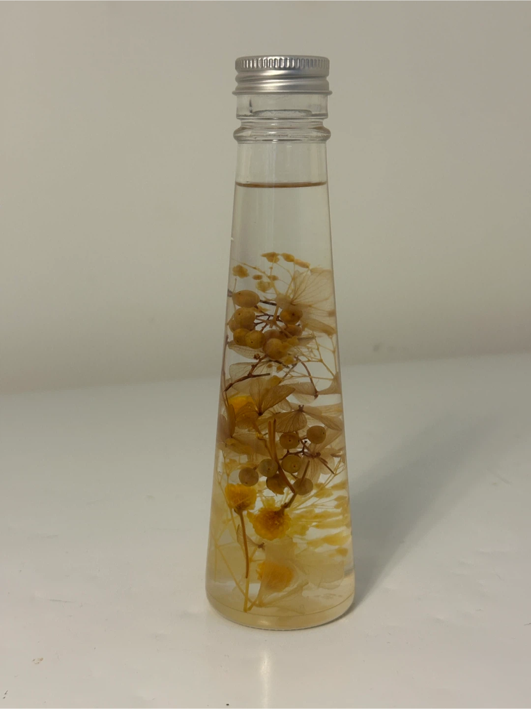 Glass bottle with dried flowers and berries