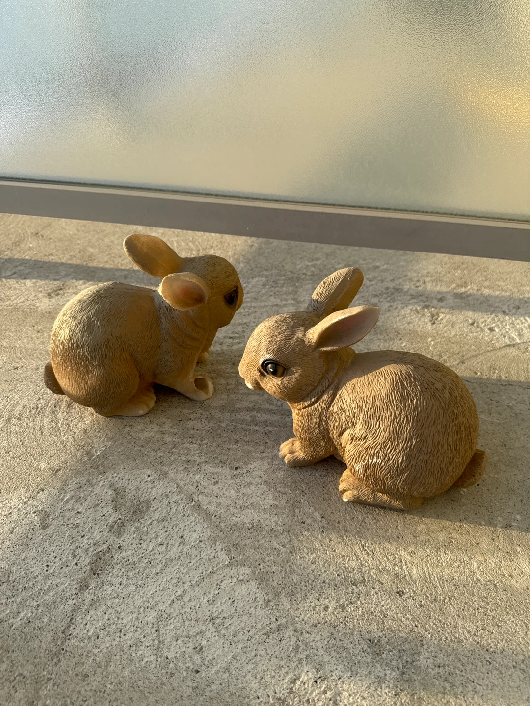 Two brown resin bunny figurines