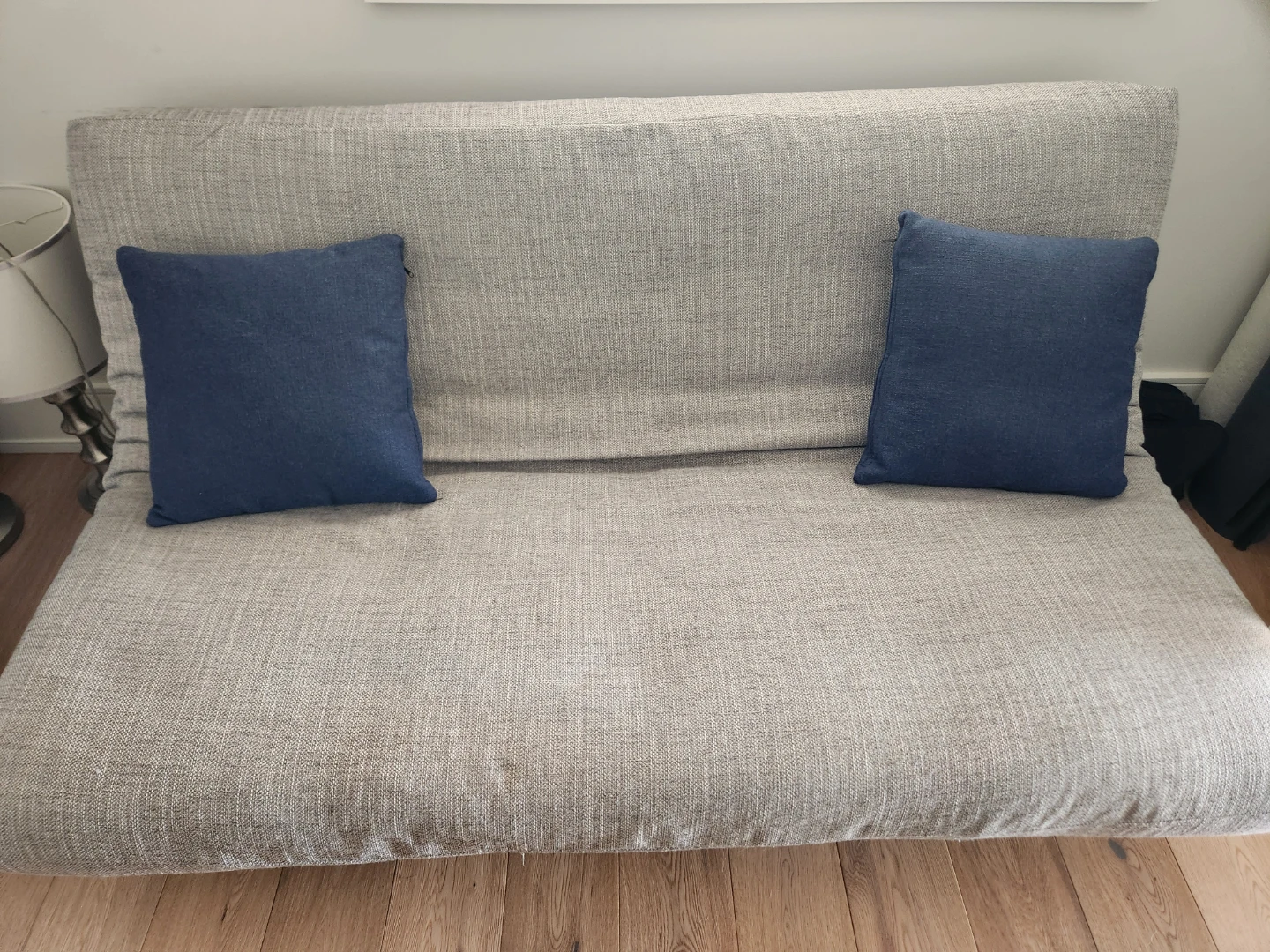 Grey futon with Two Blue Pillows