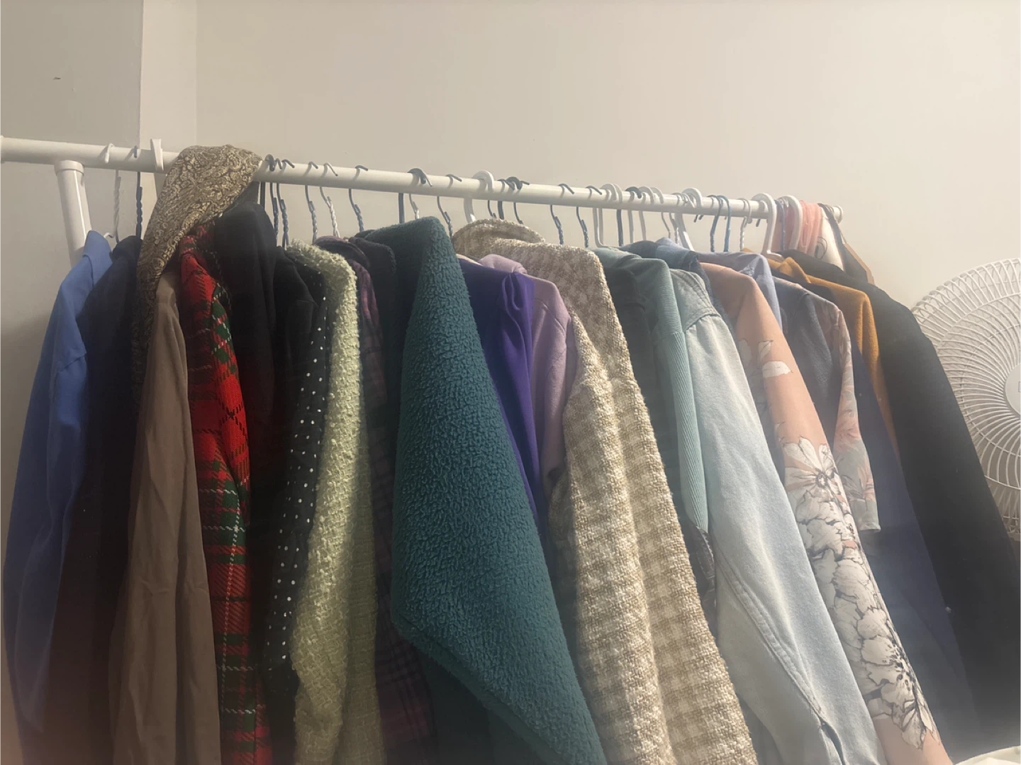 White movable clothing rack with shelf at bottom
