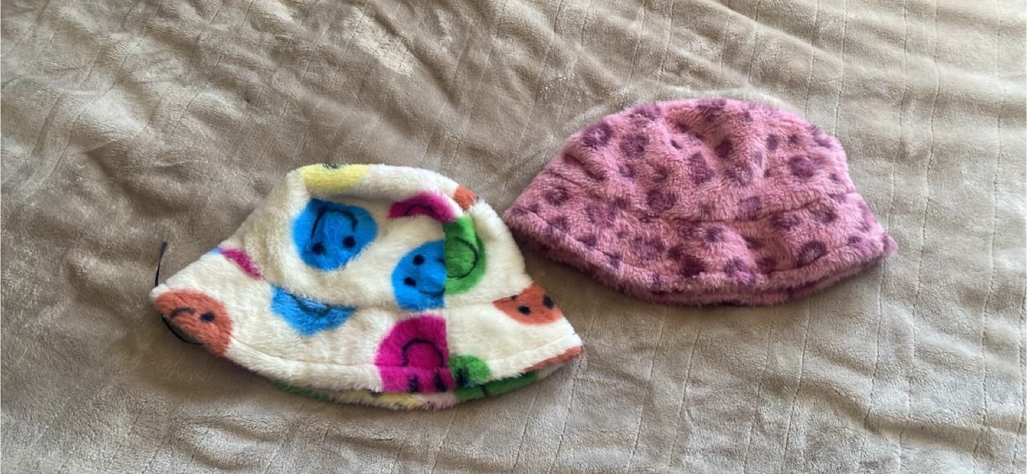 Two plush bucket hats: one with smileys, one with leopard print