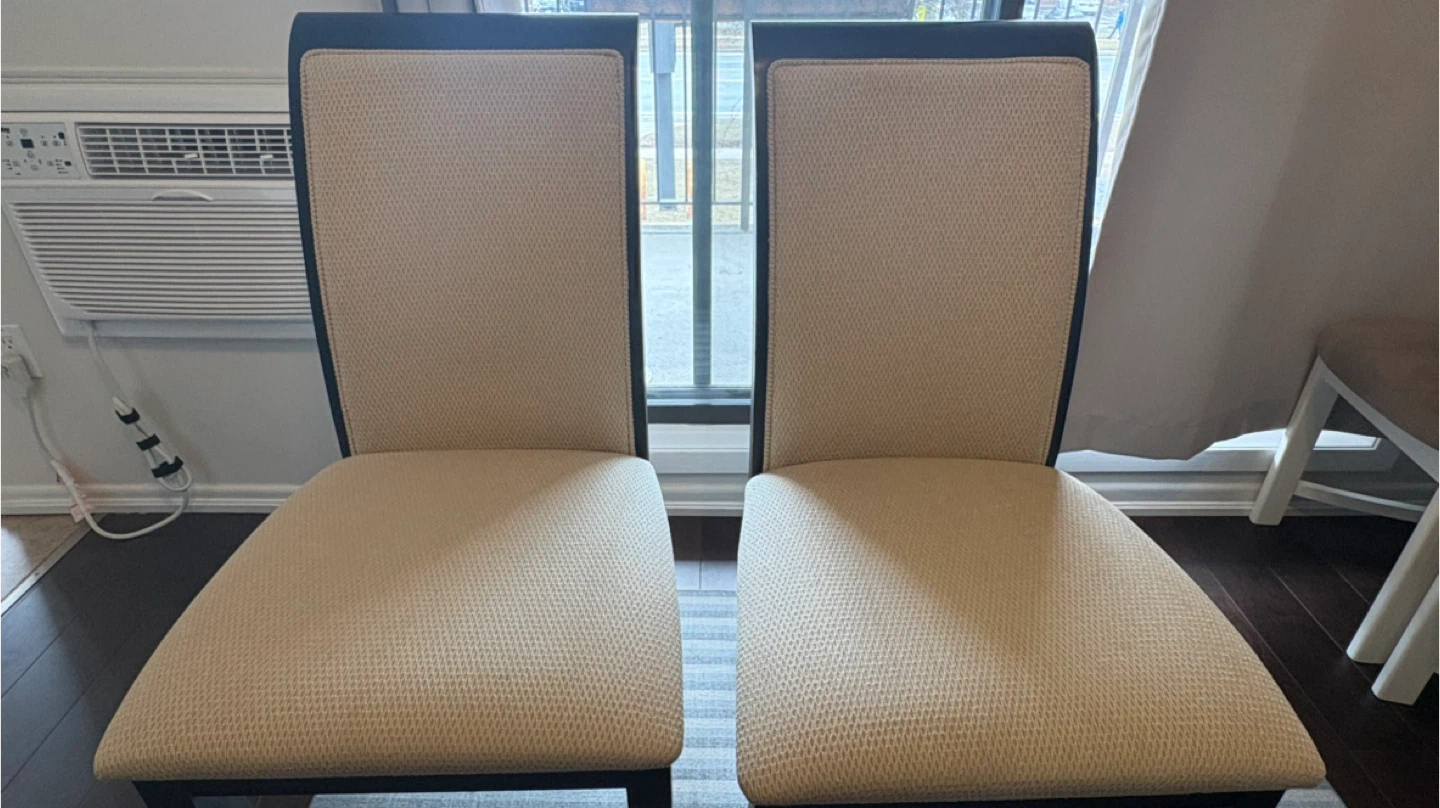 Two beige upholstered dining chairs
