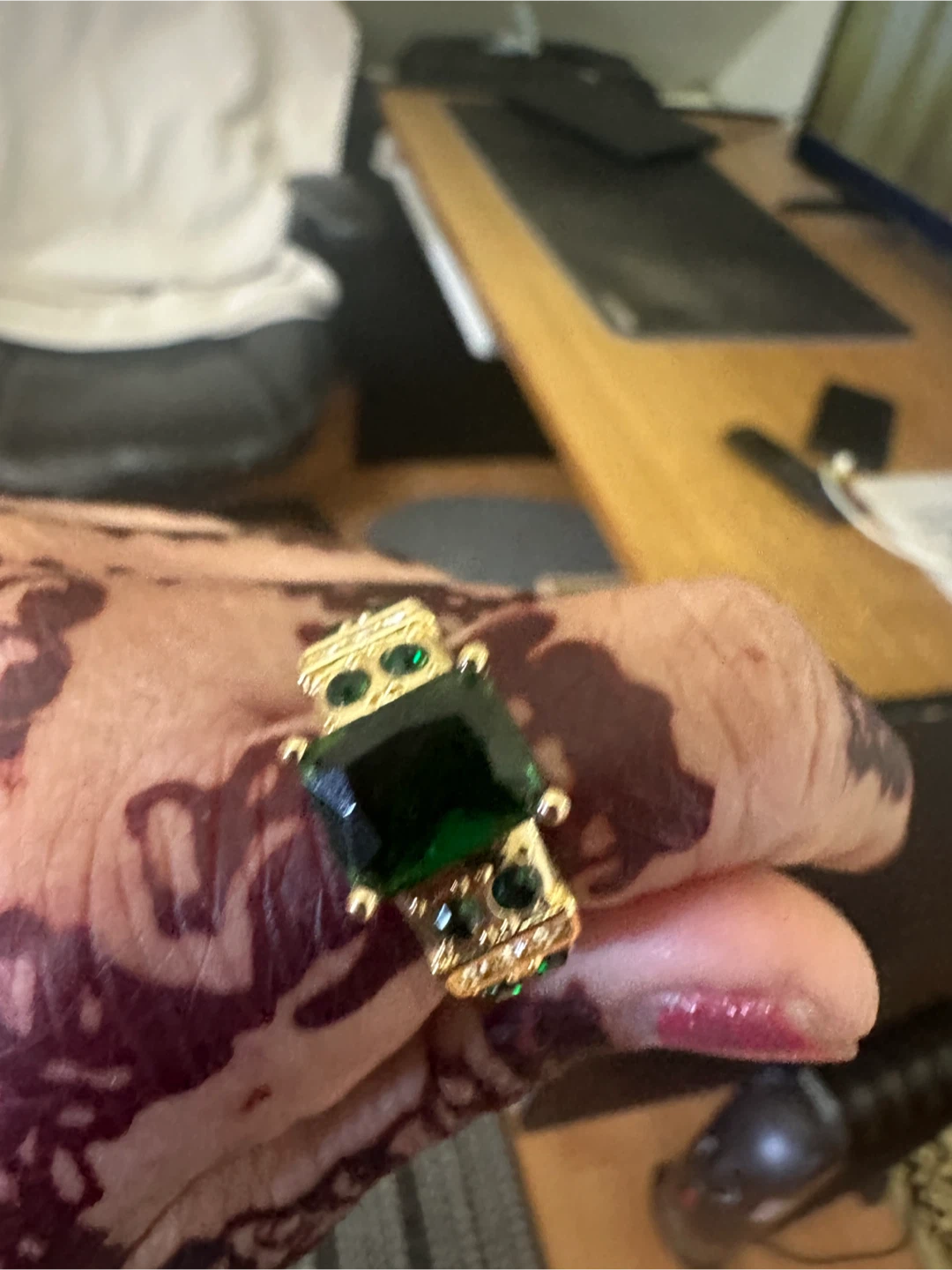 Gold tone ring with emerald-cut green stone