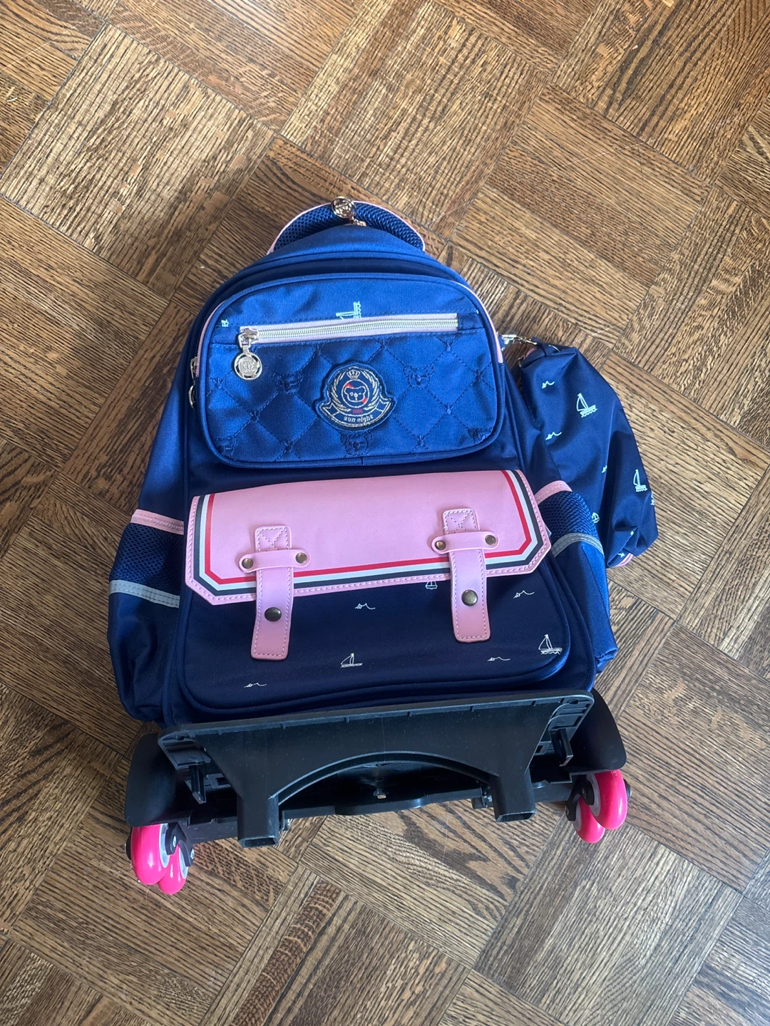 Blue rolling backpack with pink accents