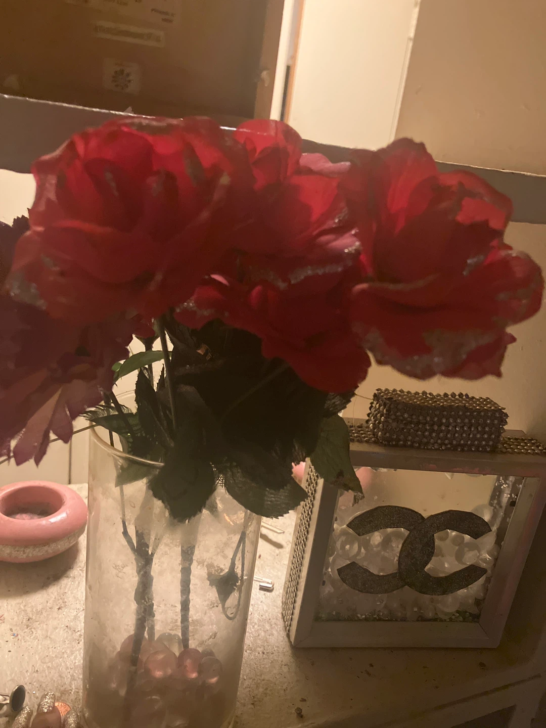 Red artificial roses in glass vase